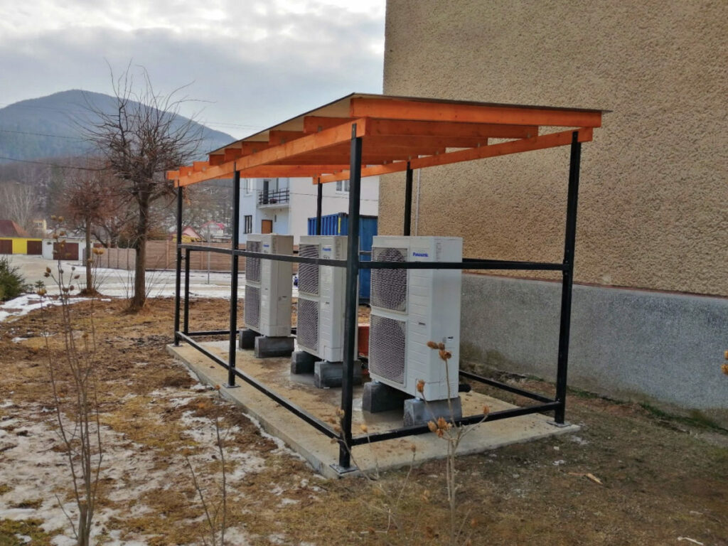 Tepelné čerpadlá umiestnené vedľa bytového domu, v zatiaľ nedokončenom prístrešku.